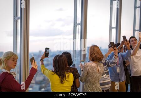 Geschäftsleute, die Selfies am Bürofenster im Hochhaus machen Stockfoto