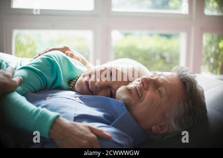 Glückliches Seniorenpaar kuscheln an sonnigen Fenster Stockfoto