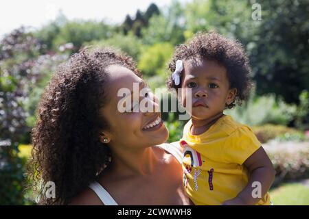 Portrait glücklich Mutter hält niedlichen Kleinkind Tochter im sonnigen Hof Stockfoto