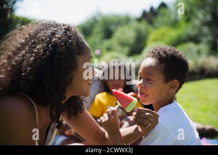 Verspielte Mutter und Sohn essen Wassermelonen-Eiszapfen auf der sonnigen Terrasse Stockfoto