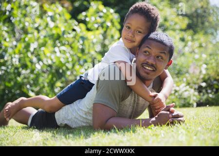 Portrait liebevoller Vater und Sohn liegen im sonnigen Sommerrasen Stockfoto