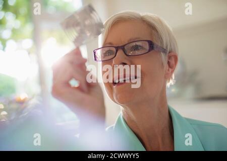 Neugierige ältere Frau untersucht Würfel im Sonnenlicht Stockfoto