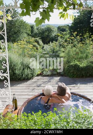 Sorgloses Paar, das sich im Whirlpool auf der sonnigen Sommerterrasse entspannen kann Stockfoto