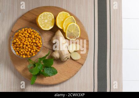 Zutaten für Sanddorntee. Sanddorn, Zitrone, Ingwer und Zitronenmelisse. Herbstgetränk. Selektiver Fokus. Draufsicht. Stockfoto