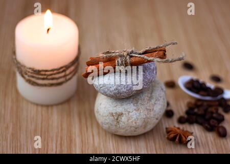 Steine mit Zimt, eine Kerze, Kaffeebohnen, ein Stern Anis. Spa-Setting-Konzept. Weichfokus Stockfoto
