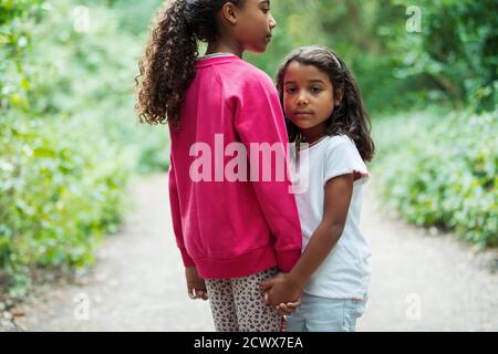 Portrait liebevolle Schwestern halten die Hände auf dem Parkweg Stockfoto