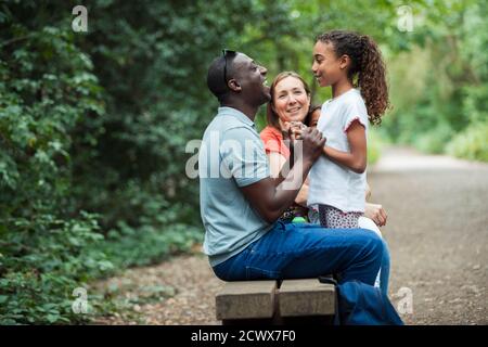 Glückliche Familie auf Parkbank Stockfoto
