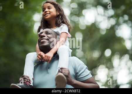 Glücklicher Vater Tochter auf den Schultern tragen Stockfoto