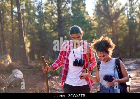 Glückliches junges Paar Wandern mit Fernglas und Kamera in sonnigen Hölzer Stockfoto