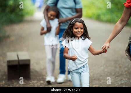 Glückliches Mädchen zu Fuß mit der Familie auf dem Weg im Park Stockfoto