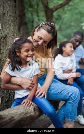 Glückliche Mutter und Tochter umarmen auf gefallenes Holz in Wäldern Stockfoto