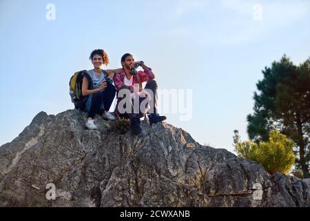 Glückliches junges Wanderpaar, das sich auf dem Felsen entspannt Stockfoto