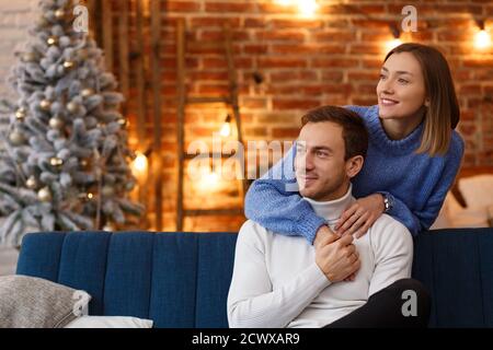 Portrait eines schönen lächelnden Paares umarmt am Heiligabend. Schöne junge Paar zu Hause genießen Zeit zusammen. Winterurlaub Stockfoto