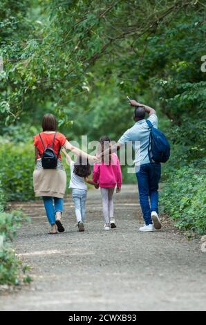 Familie hält Hände zu Fuß auf dem Weg im Park Stockfoto