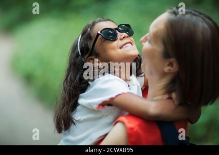 Glückliche Mutter hält Tochter in Sonnenbrille Stockfoto