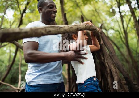 Vater und Tochter spielen mit Zweig in Wäldern Stockfoto