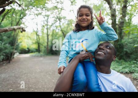 Portrait Vater trägt Tochter gestikuliert Frieden Zeichen in Wäldern Stockfoto