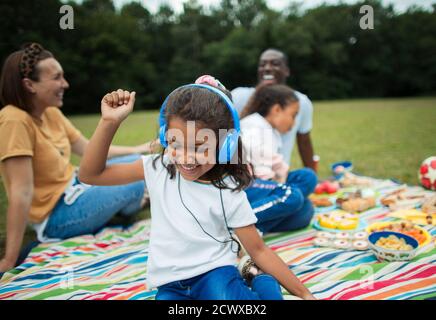 Sorgloses Mädchen, das Musik mit Kopfhörern auf der Picknickdecke hört Stockfoto