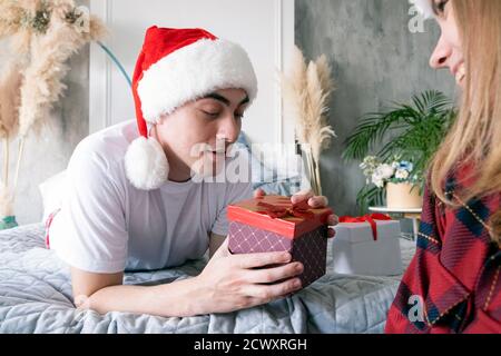Weihnachten, Urlaub, Winter und Menschen Konzept. Glückliches Paar mit weihnachtsgeschenk zu Hause tragen weihnachtsmützen. Stockfoto
