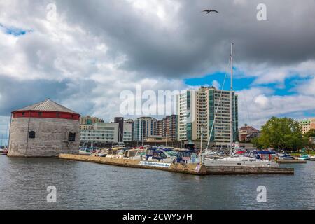 Shoal Tower, Kingston, Ontario, August 2014 - Boote und Kalkstein Befestigung am Wasser mit Stadtgebäuden im Hintergrund Stockfoto