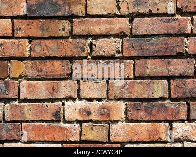 Eine rustikale, gealterte, wettergetragene rote Ziegelwand für einen strukturierten grafischen Designhintergrund Stockfoto
