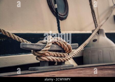 Nahaufnahme der Verankerungsklamotte mit einem Boot Seil um ihn gebunden. Verbindung visuelles Konzept als Boot gebunden und mit dem Ponton verbunden. Stockfoto