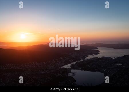 Stadtbild mit Fjord und Sonnenuntergang hinter Bergen im Horizont. Luftaufnahme. Panorama. Stockfoto