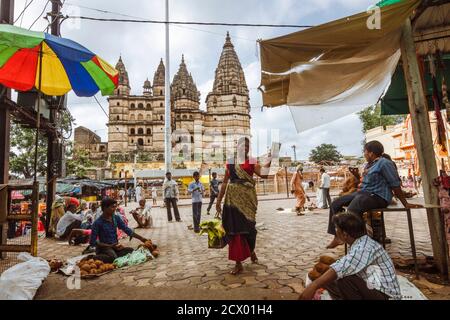 Orchha, Madhya Pradesh, Indien: Straße Markt Szene mit Chaturbhuj Tempel im Hintergrund. Der Tempel ist eine komplexe mehrstöckige Struktur, die sich mit dem Tempel vermischt Stockfoto