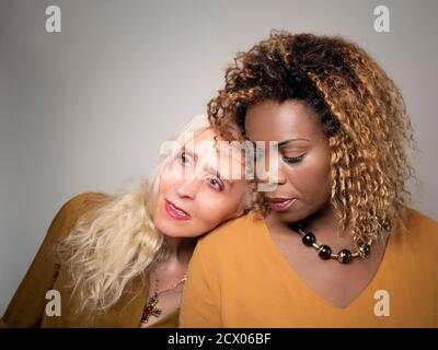 Horizontales Porträt einer weißen Frau, auf der ihr Kopf liegt Die Schulter ihrer schwarzen Freundin Stockfoto