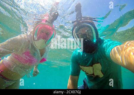 Junges Paar in Vollgesichtsmasken zum Schnorcheln macht Selfie unter Wasser. Stockfoto