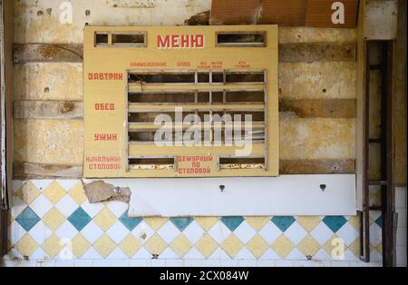 15. September 2020, Brandenburg, Trebbin/OT Glau: Blick in ein baufälliges Haus am Rande der Gemeinde im Landkreis Teltow-Fläming. An der Wand hängt ein Brett mit der Aufschrift "Menu" Menü, in russischer Sprache. Nach dem Ersten Weltkrieg wurde hier mit der Friedensstadt Weißenberg aus Spenden eine religiöse Siedlung mit medizinischen, sozialen und pädagogischen Einrichtungen gegründet. Während der NS-Zeit wurden die Eigentümer enteignet und die Bewohner vertrieben. Nach dem Ende des Zweiten Weltkriegs stationierte die Rote Armee hier eine Garnison mit einer Pioniereinheit und Raketentruppen und einer Mili Stockfoto