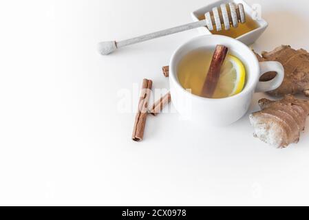 tasse Infusion und Zutaten wie Ingwer, Zitrone, Zimt und Honig auf der Oberseite eines weißen Tisches. Konzept der Hausmittel Stockfoto