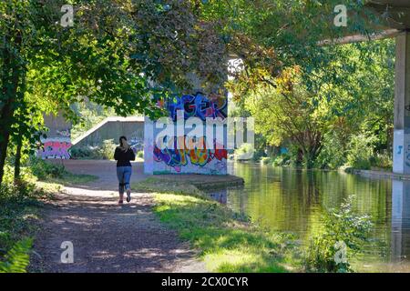 Rückansicht einer jungen Läuferin auf dem Abschleppweg Des Wey-Schifffahrtskanals bei New Haw Surrey England VEREINIGTES KÖNIGREICH Stockfoto