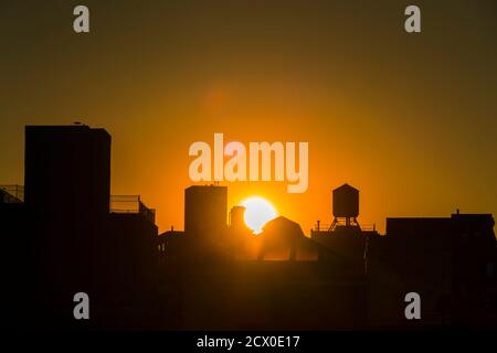 Die Sonne untergeht unter den East Village Gebäuden in New York City. Stockfoto