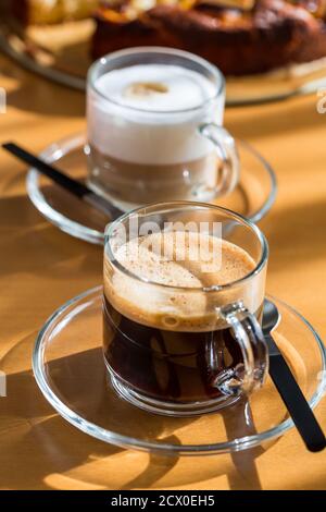 Zwei Tassen Kaffee und Cappuccino mit Kuchen auf Holztisch. Stockfoto