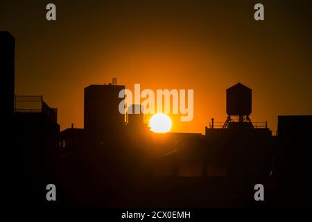 Die Sonne untergeht unter den East Village Gebäuden in New York City. Stockfoto