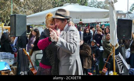 EIN ÄLTERES PAAR TANZT EINEN TANGO AUF DER STRASSE UMGEBEN VON VIELEN TOURISTEN Stockfoto