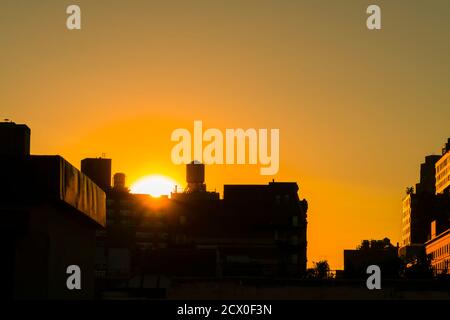 Die Sonne untergeht unter den East Village Gebäuden in New York City. Stockfoto