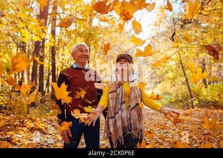 Herbstsaison. Familienpaar wirft Blätter im Herbstwald. Ältere Menschen haben Spaß im Freien genießen Natur spielen Stockfoto