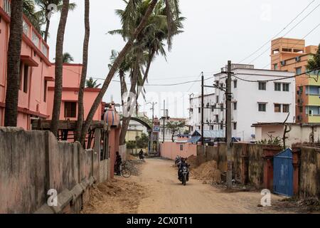 Puri, Indien - 3. Februar 2020: Nicht identifizierte Personen fahren am 3. Februar 2020 auf einer kleinen Feldstraße neben Wohnhäusern Motorräder Stockfoto