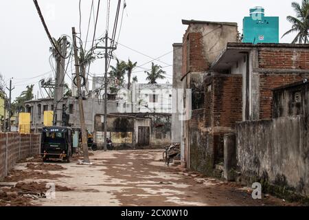 Puri, Indien - 3. Februar 2020: Eine ländliche und leere Straße mit geparkten cng-Rikschas neben verschiedenen Gebäuden am 3. Februar 2020 in Puri, Indien Stockfoto