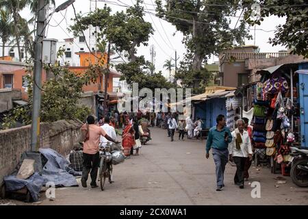 Puri, Indien - 3. Februar 2020: Ein paar unbekannte Menschen gehen am 3. Februar 2020 in Puri, Indien, auf einer kleinen asphaltierten Straße neben Geschäften Stockfoto