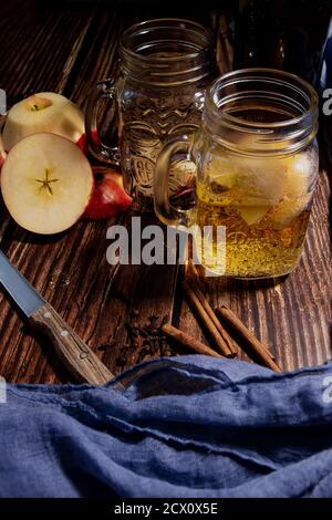 Ein Holztisch mit Äpfeln und einem leckeren Apfelwein. Typisches Herbstgetränk Stockfoto