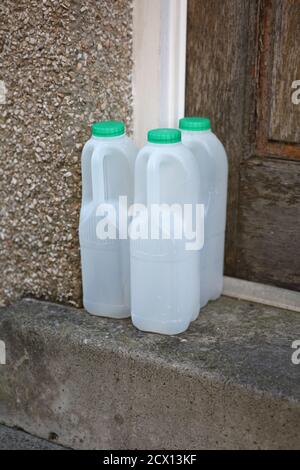 Leere Plastikmilchflaschen vor der Haustür Stockfoto
