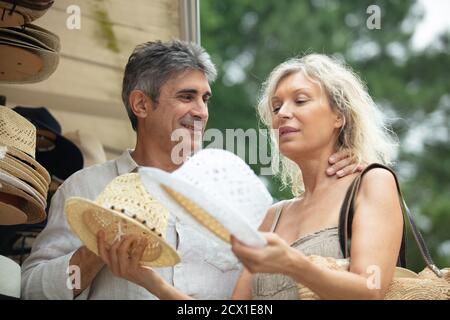 Zufriedene junge Frau und Mann Wahl Hüte im Geschäft Stockfoto