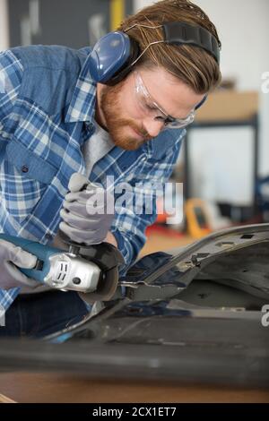 Junger Schweißer mit einem Winkelschleifer in der Garage Stockfoto