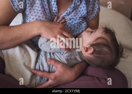 Säugling zufrieden starrt Mutter während des Stillens Stockfoto