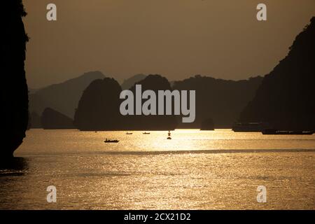 Boote in der Ha Long Bay bei Sonnenuntergang, Vietnam Stockfoto