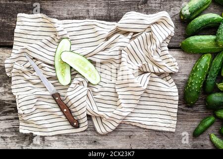 Draufsicht frische Bauerngurken, Messer, Handtuch, Gurke auf Holzhintergrund, Mockup, Kopierraum. Stockfoto