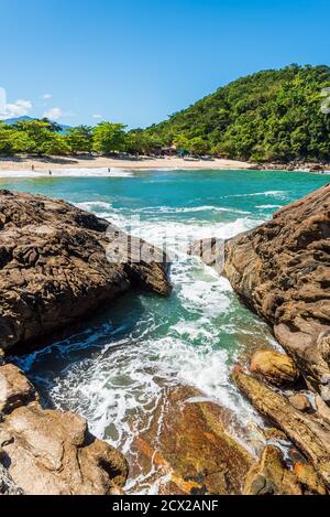 Kleiner Strand in einer wilden tropischen Landschaft aus der Ferne gesehen Von Felsen am Ufer Stockfoto